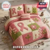 Breast Cancer Awareness Quilted 3-Piece Bedding Set with pink ribbons, floral patterns, and green leaf motifs on a bed.