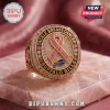 Buffalo Bills Breast Cancer Awareness ring featuring a pink ribbon, gold metal, and inset pink crystals on quartz stone.