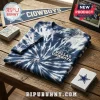 Dallas Cowboys America's Team Tie-Dye Shirt in navy and white spiral pattern on a wooden surface with NFL memorabilia.