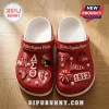 Delta Sigma Theta Red Crocs With Charms featuring Greek letters, 1913, and sorority-themed emblems on a wooden surface.