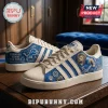 Detroit Lions Motor City Casual Sneakers featuring blue and cream panels, lion graphics, and football motifs on a table.