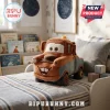 Disney Pixar Cars Tow Mater plush pillow featuring a brown and grey truck design sitting on a striped bed in a bedroom.