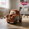 Disney Pixar Cars Tow Mater plush pillow in rust and blue fabric sitting on a wooden nursery floor with soft lighting.