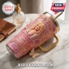 Dolly Parton 1946-2026 Pink Rhinestone 40oz Tumbler with portrait, butterfly charm, and gold handle on marble surface.