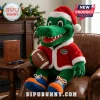 Florida Gators Santa Mascot Christmas Plush Toy wearing a red coat and hat while holding a football in a leather chair.