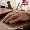 Harry Potter 25th Anniversary Gold Engraved Ring featuring colorful enamel inlays worn on a hand over a wooden desk.
