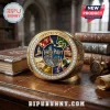Harry Potter 25th Anniversary Gold Engraved Ring featuring a multi-colored magical emblem with crystals on a wooden desk.