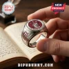 Harry Potter Gryffindor 25th Anniversary Engraved Ring with red enamel crest, held over an open vintage book page.