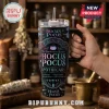 Hocus Pocus Sanderson Sisters Halloween Stanley Tumbler with apothecary graphics and black handle in a hand.