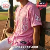 Los Angeles Dodgers x Breast Health Awareness pink baseball jersey worn by a man on a wooden dugout bench.