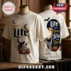 Miller Lite Halloween Skeleton T-Shirt 2026 featuring cream fabric with a graphic of a beer can, moon, and skeleton hand.