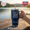 New England Patriots 1776-2026 America 250 Stanley Tumbler in navy blue with logo, metal straw, and handle on wooden pier.
