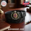 Omega Psi Phi Limited Edition Leather Belt with black embossed floral pattern and a metal crest buckle on a wooden desk.