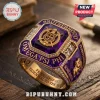 Omega Psi Phi Purple Amethyst Gold Ring featuring a central crest, gold emblem, and engravings on a wooden surface.
