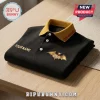 Ozzy Osbourne custom name embroidered black polo shirt with yellow collar and gold bat emblem on folded fabric.