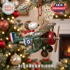 Peanuts Snoopy Flying Ace Christmas Tree Ornament in a green vintage biplane with red scarf against a blurred tree.