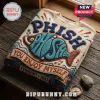 Phish Vermont 1983 embroidered ugly sweater on a rustic wooden table with a fish graphic and music notes in blue and tan.