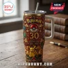 Pokemon 30th Anniversary Stainless Steel Tumbler 40oz with gold, red, and brown embossed character design on wooden table.