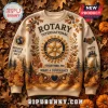Rotary International Service Above Self beige ugly sweater featuring a central gear logo, autumn leaves, and forest motifs.