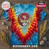 San Francisco 49ers x Grateful Dead mascot shirt with red, yellow, and blue tie-dye pattern on a wooden surface.