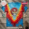San Francisco 49ers x Grateful Dead mascot shirt with red, yellow, and blue tie-dye pattern on a wooden background.
