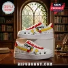 Snoopy Peanuts White Air Force 1 Low Top sneakers with comic strip prints, red accents, and yellow swooshes on a desk.