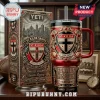 St Kilda Saints YETI Stanley Tumbler with red, black, and gold ornate crest and box featuring the club motto on wood surface.