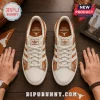 Texas Longhorns Burnt Orange leather sneakers featuring white stripes and team logos on a dark wood background.