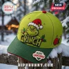 The Grinch Merry Grinchmas 2026 Holiday Cap in lime green with embroidered character, red brim, and winter forest background.