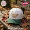 The Legend of Zelda Triforce Embroidered Cap in white with a dark green brim and gold front emblem on a wooden bench.