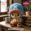 Tony Tony Chopper One Piece stuffed plush toy wearing a blue hat with an X emblem and brown antlers on a wooden desk.