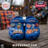 University of Florida Gators Blue Crocs with team-themed charms featuring logos, a mascot, jersey, and stadium on a table.