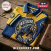 University of Michigan Wolverines Textured Polo Shirt in maize and blue with a wolverine mascot logo on a wood background.