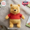 Winnie the Pooh Soft Plush Toy wearing a red shirt, sitting on a textured grey knit blanket with books in the background.