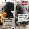 Xenomorph Crochet Emotional Support Plush Toy in dark grey yarn holding a small orange crocheted cat on a wooden surface.