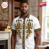 Man wearing an Alpha Phi Alpha Egyptian button down Hawaiian shirt with sphinx, gold laurel, and Greek letter motifs.