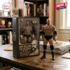 Andy Williams The Butcher AEW action figure standing next to its black collector box on a wooden table.