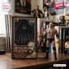 Andy Williams The Butcher AEW action figure standing next to its collectible display box on a wooden desk surface.