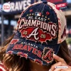 Close-up of a person wearing an Atlanta Braves 2026 Champions distressed cap with frayed edges and embroidered patches.