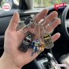Hand holding a Batman 1966 Classic TV Series Batmobile keychain with charms of the vehicle, two characters, and a tag.