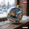 Close-up of a Gotham City Christmas ornament featuring heroes and a car inside a clear sphere on a snowy windowsill.