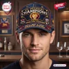 Front view of a man wearing the Brisbane Lions 2026 Three-Peat Championship Cap in a room setting.