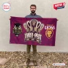 Man holding a maroon Brisbane Lions AFL 2026 Premiers house flag outdoors.