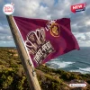 Outdoor view of Brisbane Lions AFL 2026 Premiers maroon house flag waving on a pole near the ocean.