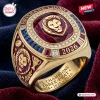 Closeup of Brisbane Lions AFL Gold Championship Ring with red stone, lion emblem, and 2026 text.