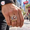 Closeup of Brisbane Lions AFL Gold Championship Ring worn on hand outdoors.