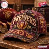 Closeup of the Brisbane Lions AFL Premiers distressed cap featuring embroidered text and logos on a wooden surface.