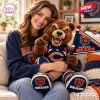 Smiling woman holding a Chicago Bears plush mascot pillow wearing a team jersey.