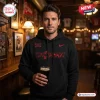 Front view of a man holding a drink while wearing the Cincinnati Bearcats City Within Red Hoodie in a tavern.