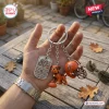 Close-up of a hand holding the Cleveland Browns 80th Anniversary Metal Keychain with three charms outdoors.